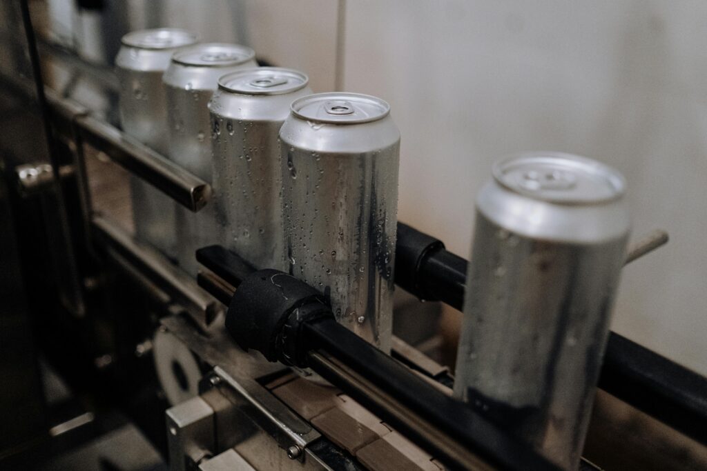 Close-up of aluminum cans with water droplets on a production line, showcasing industrial beverage processing.