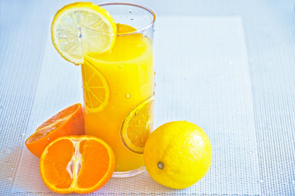 Vibrant citrus juice in a glass with fresh orange and lemon slices, offering a refreshing taste of summer.